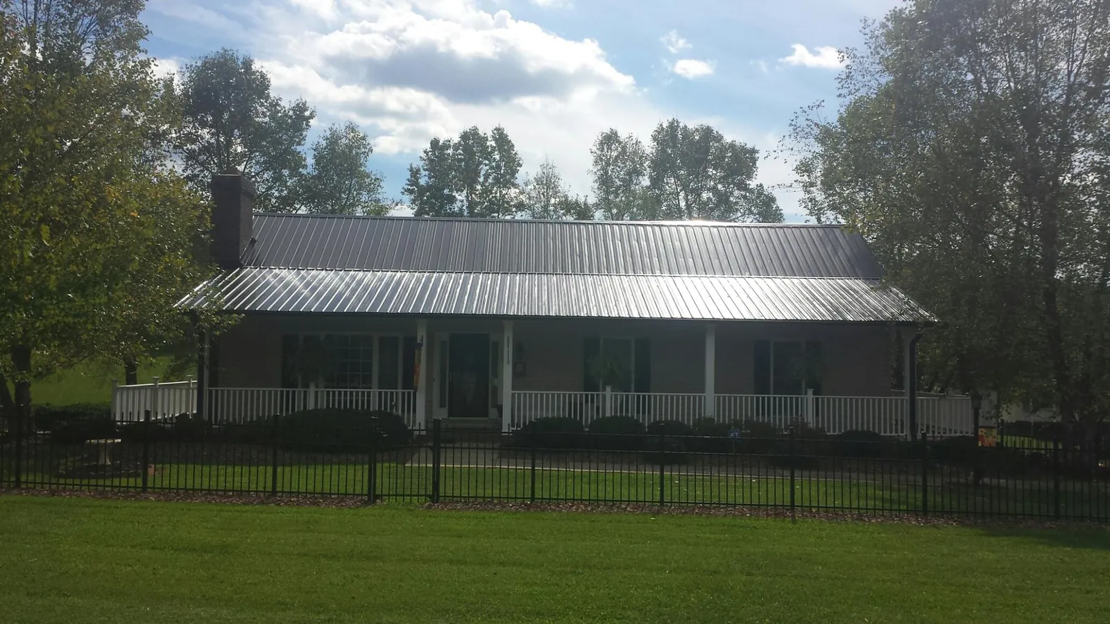 Gray metal roof on a brick ranch with a full width front porch — Gutter Guard Installation work by our crew in Patton